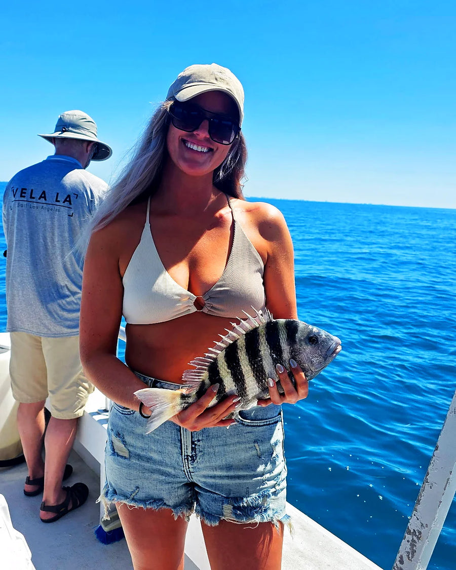 Female guest smiling with a fish on an inshore charter